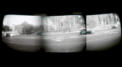 A quad pano night vision view from inside a vehicle showing a road intersection with trees, cars, and traffic lights, framed by a dark border.