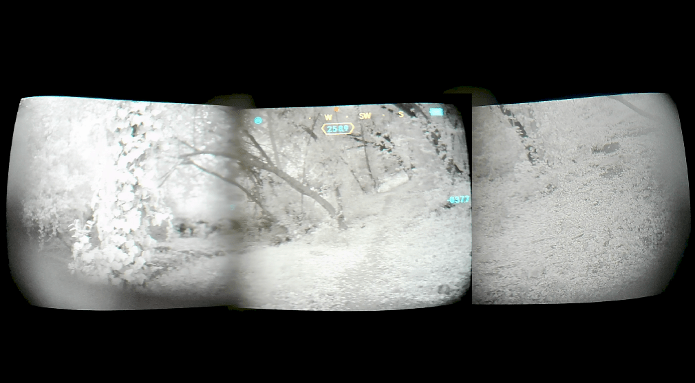 A quad pano night-vision style outdoor scene showing snow-covered trees and ground, with a black surround and small cyan interface marks near the top center.